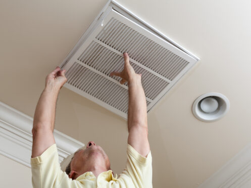 A man checking the AC vent filter